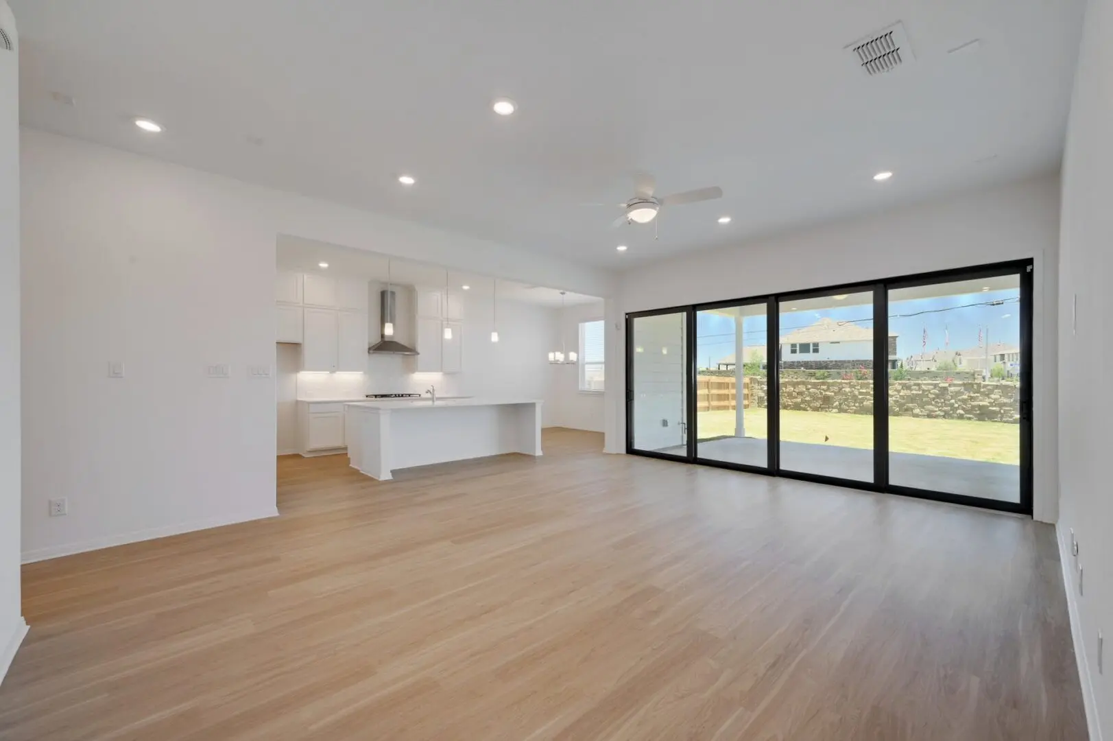 An empty living room with hardwood floors and sliding glass doors.