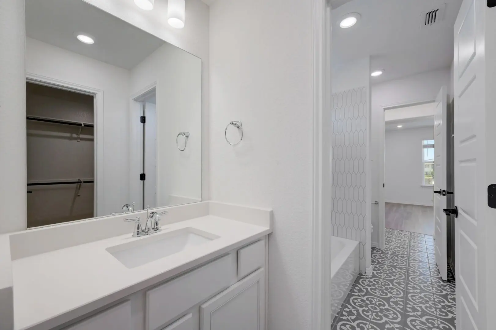 A white bathroom with a sink and mirror.