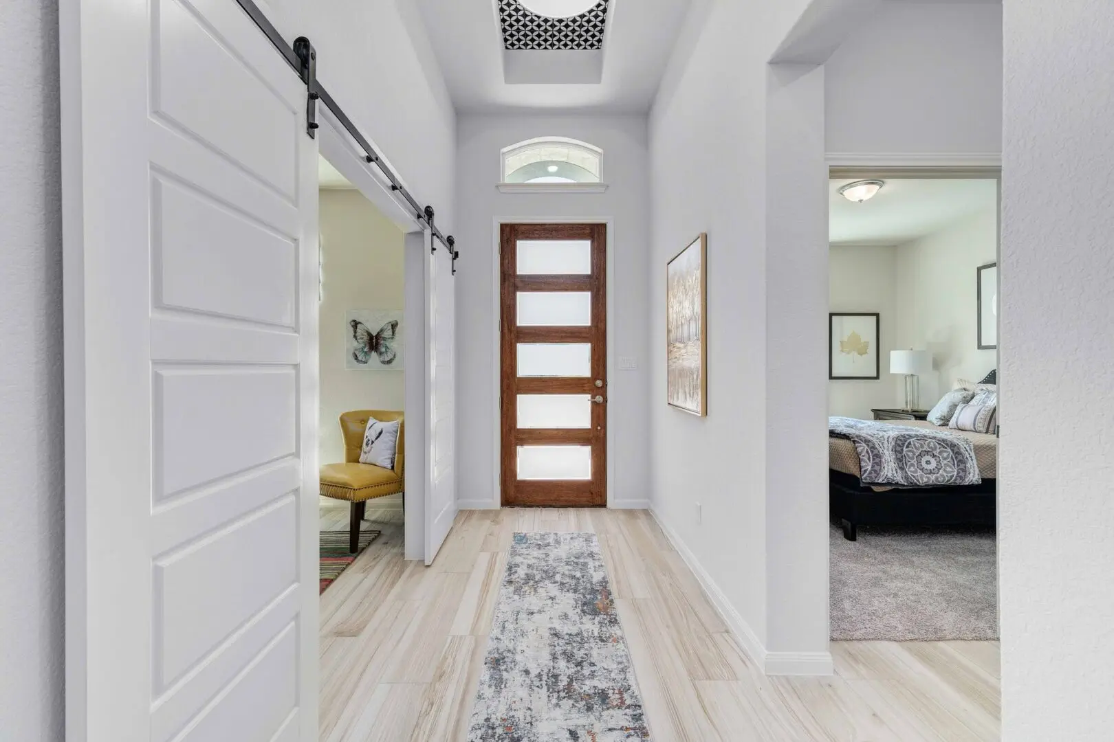 A hallway in a home with wooden floors and a door.