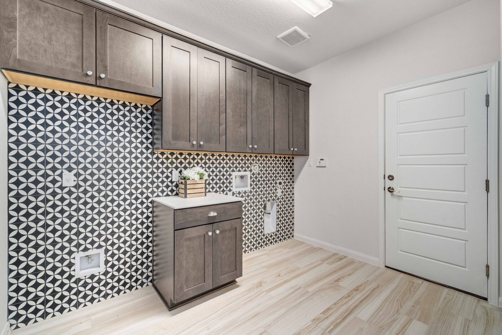 A laundry room with tiled walls and cabinets.