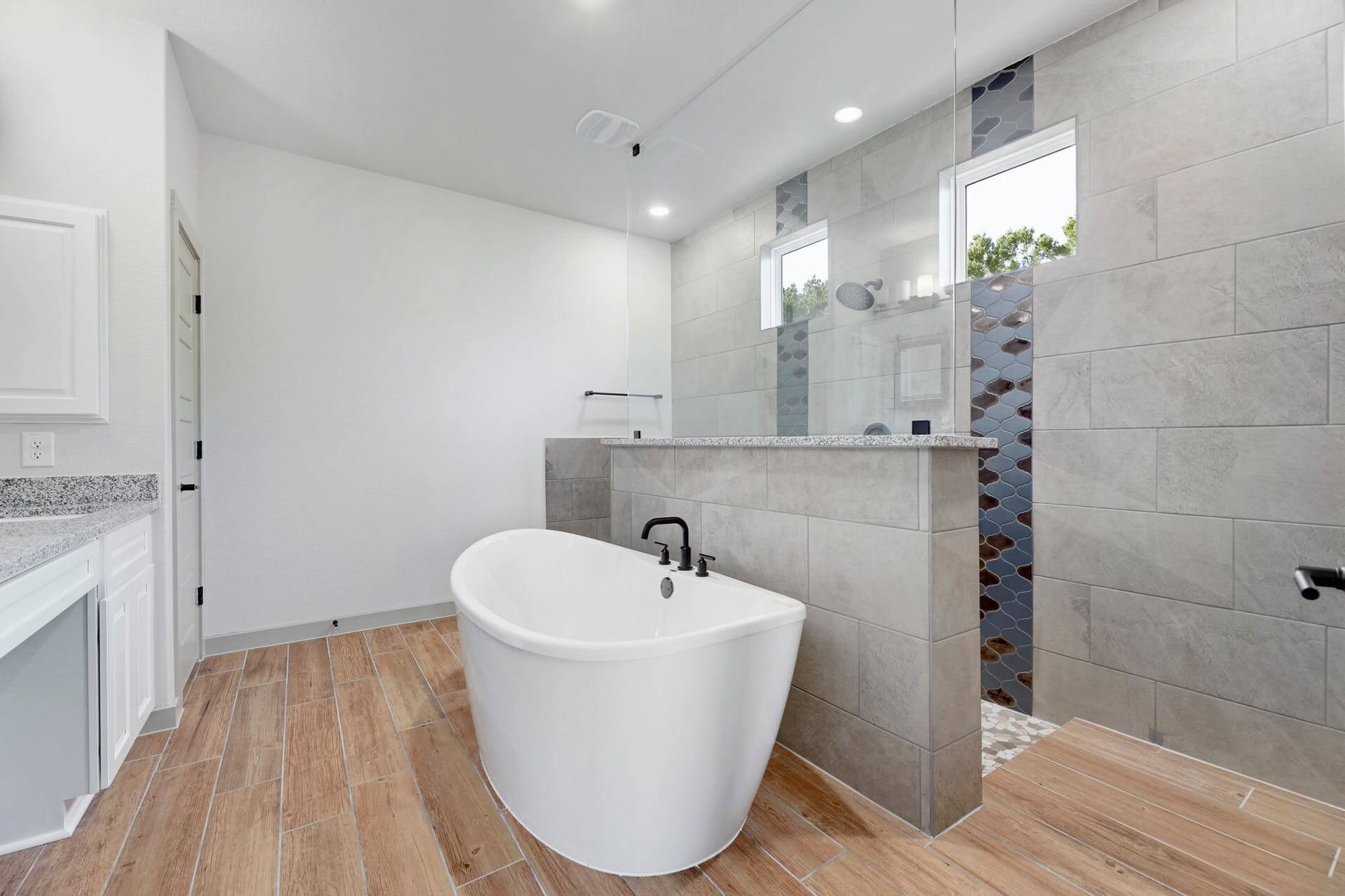 A modern bathroom with a white tub and wood floors.