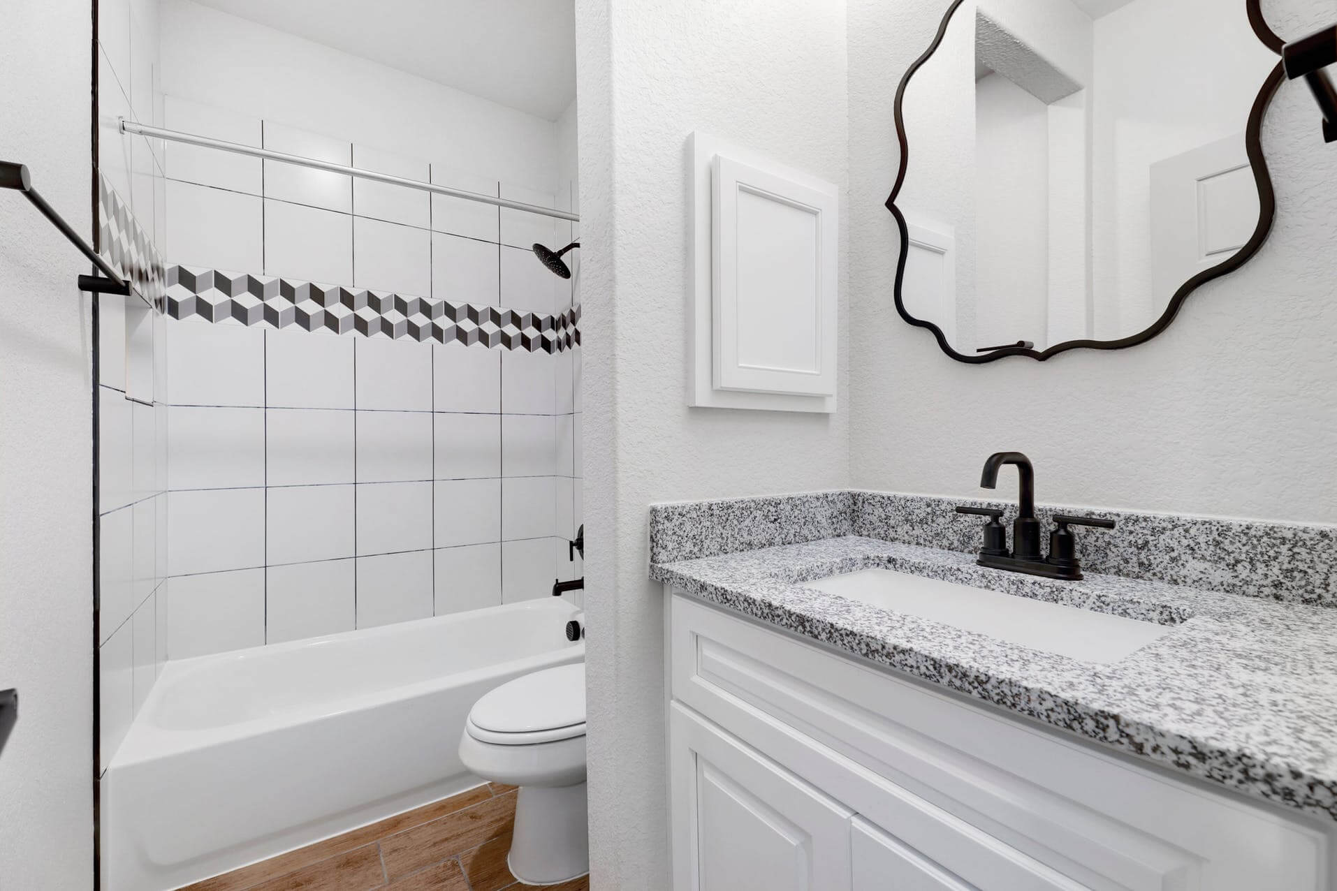 A bathroom with black and white tile and a mirror.