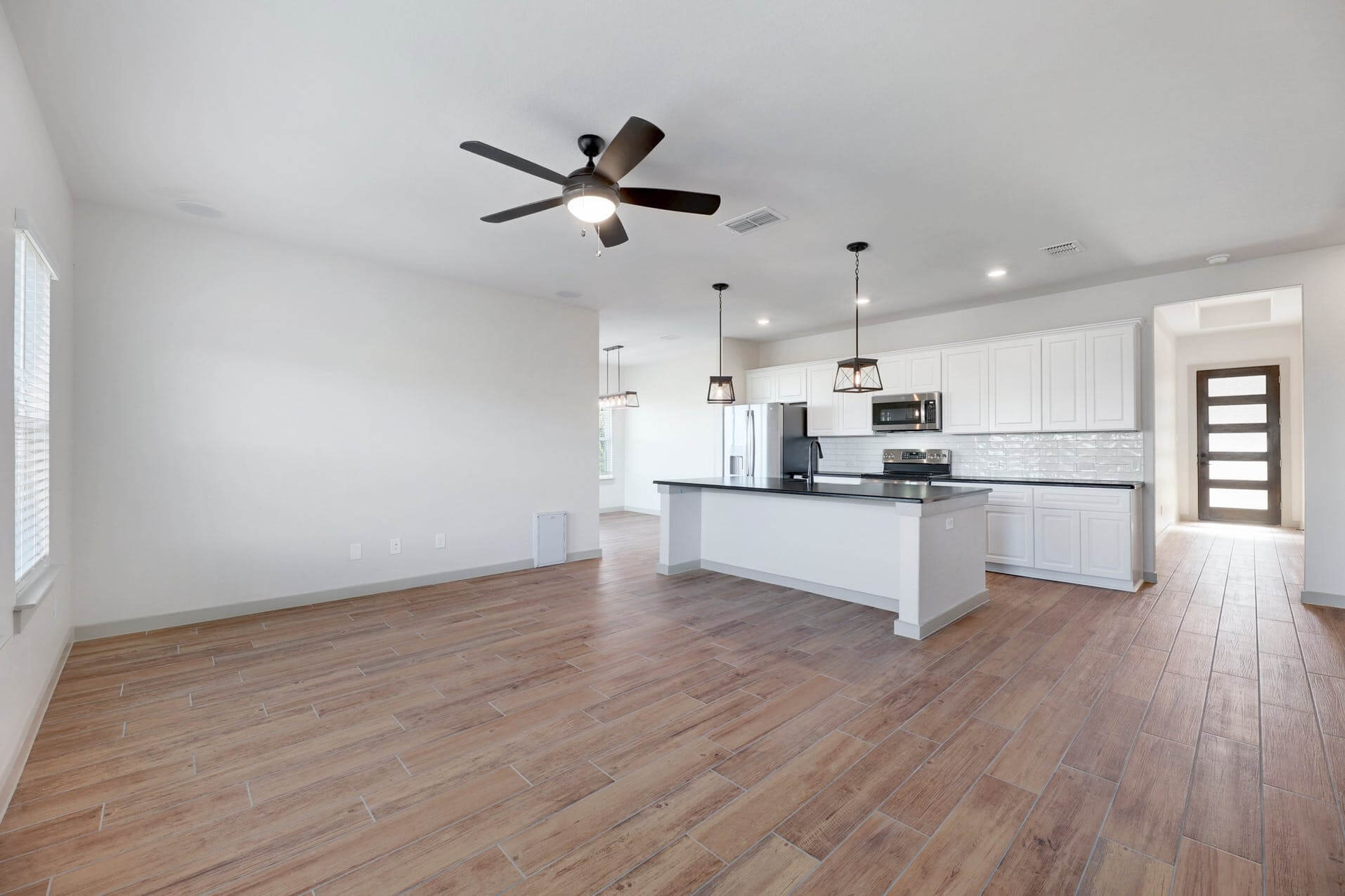 An empty kitchen with wood floors and a ceiling fan.